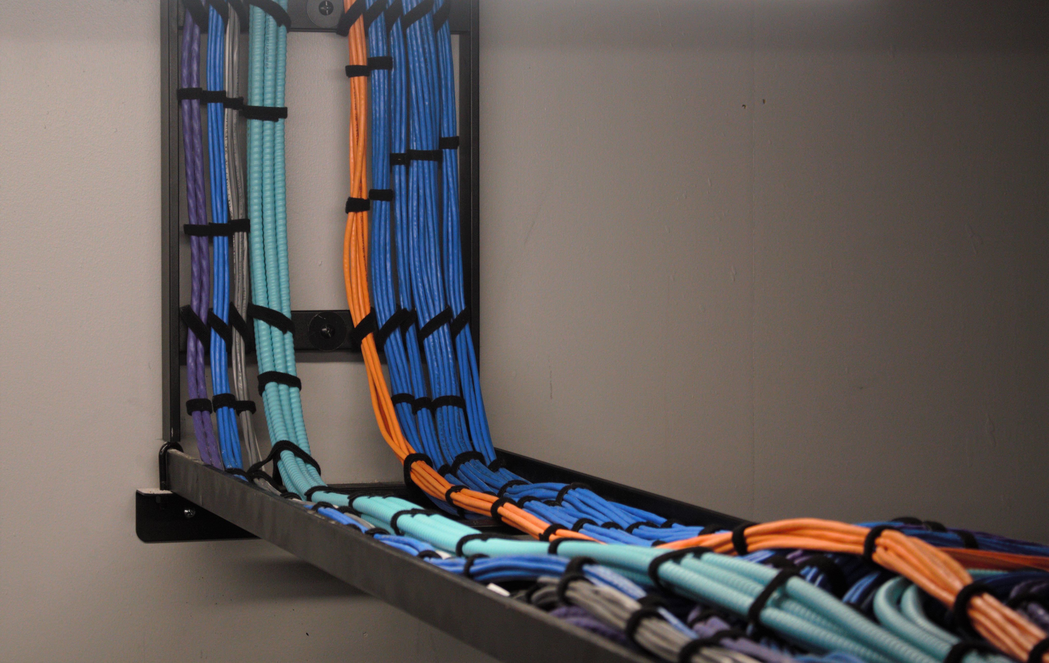 Professional low-voltage cable management system with organized color-coded data and telecommunications cables